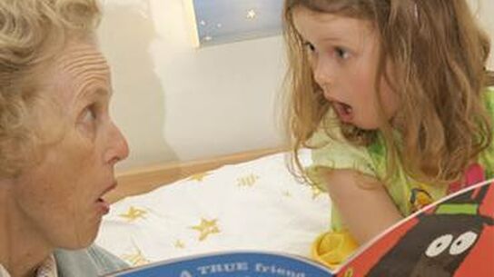 A girl reading a book with her grandmother.