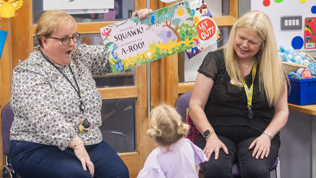 Two professionals reading to a young child.