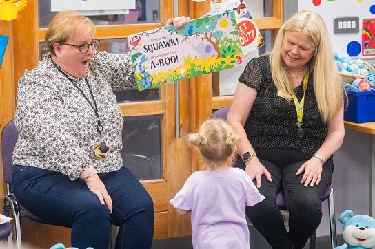 Two professionals reading to a young child.