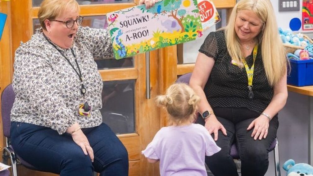 Two professionals reading to a young child.