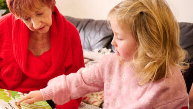 A grandmother reading with her granddaughter at home