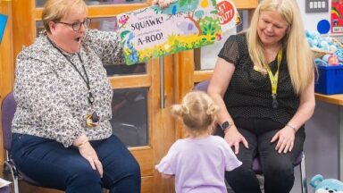 Two professionals reading to a young child.