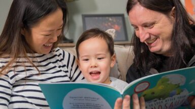 Carers and child reading together