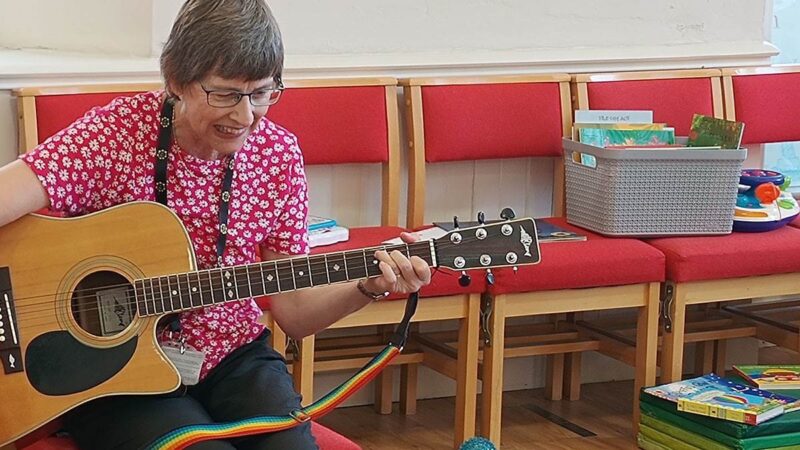 A lady at the session playing the guitar.