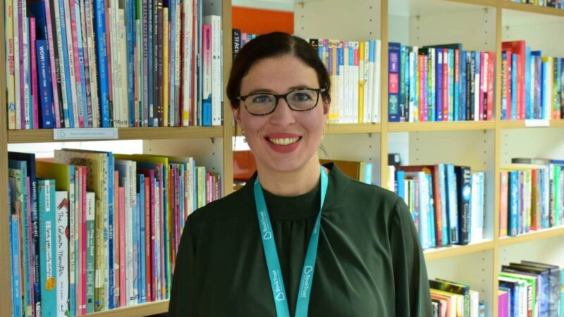 Lizzie smiling and looking to camera with books in the background.